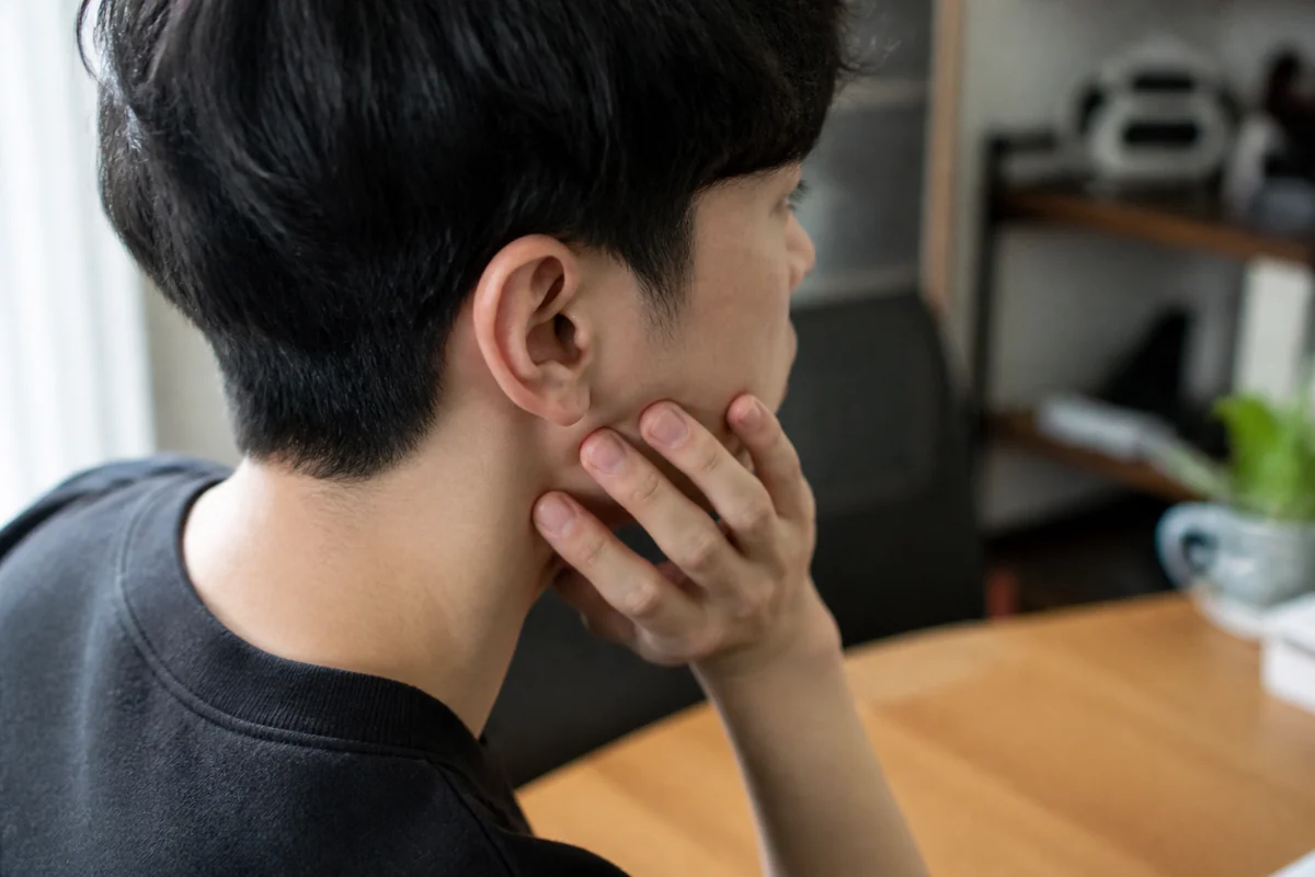 턱 주변이 불편해 손으로 턱을 짚은 20대의 옆모습