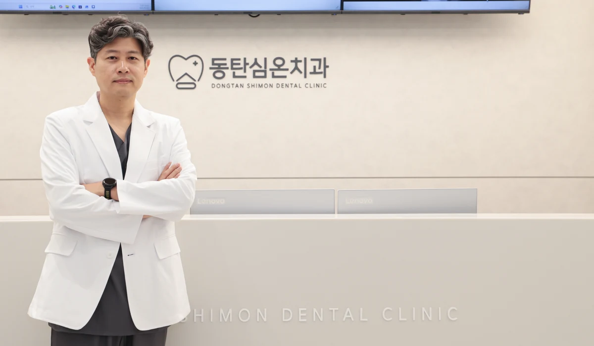 동탄심온치과 로고 벽 앞에 선 치주과 전문의 심재용 대표원장